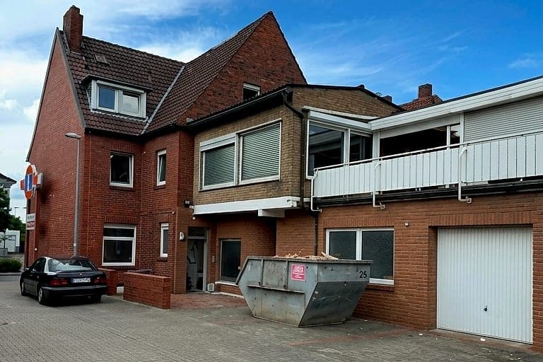 Klinkerhaus vor der Sanierung: verglaster Vorbau über der Garage, Bauschuttcontainer auf dem Vorplatz